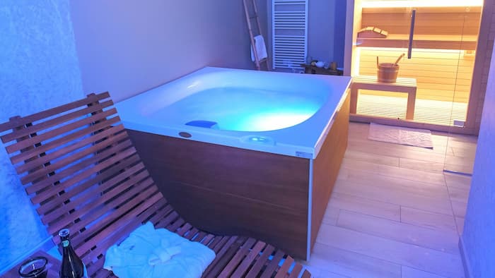 Vista dell\'interno della SPA con sdraio, vasca idromassaggio e suana. Si nota anche effetti di luce per la cromoterapia.